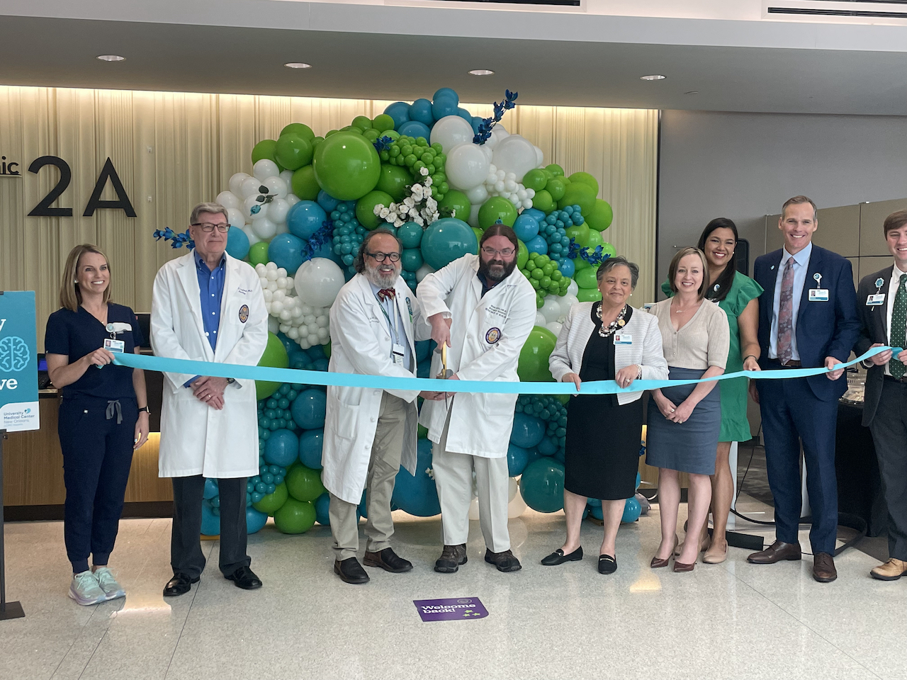 This image shows a group of people cutting the ribbon on a new clinic space
