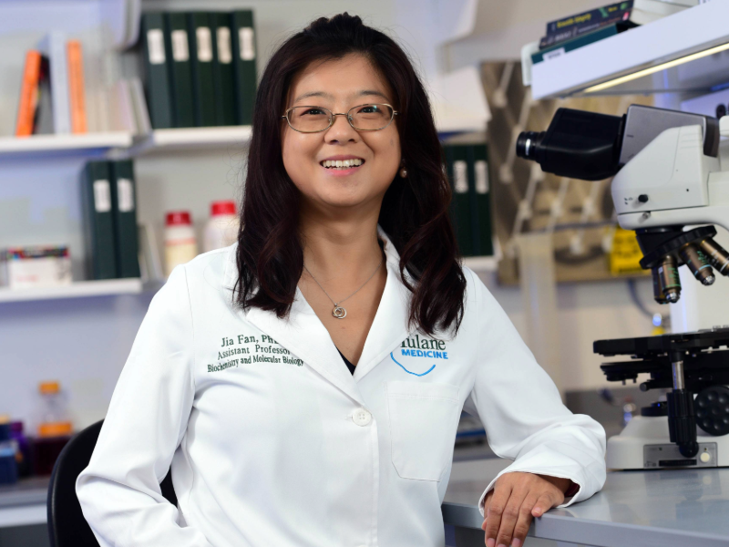 Researcher Jia Fan stands in a lab wearing a white lab coat
