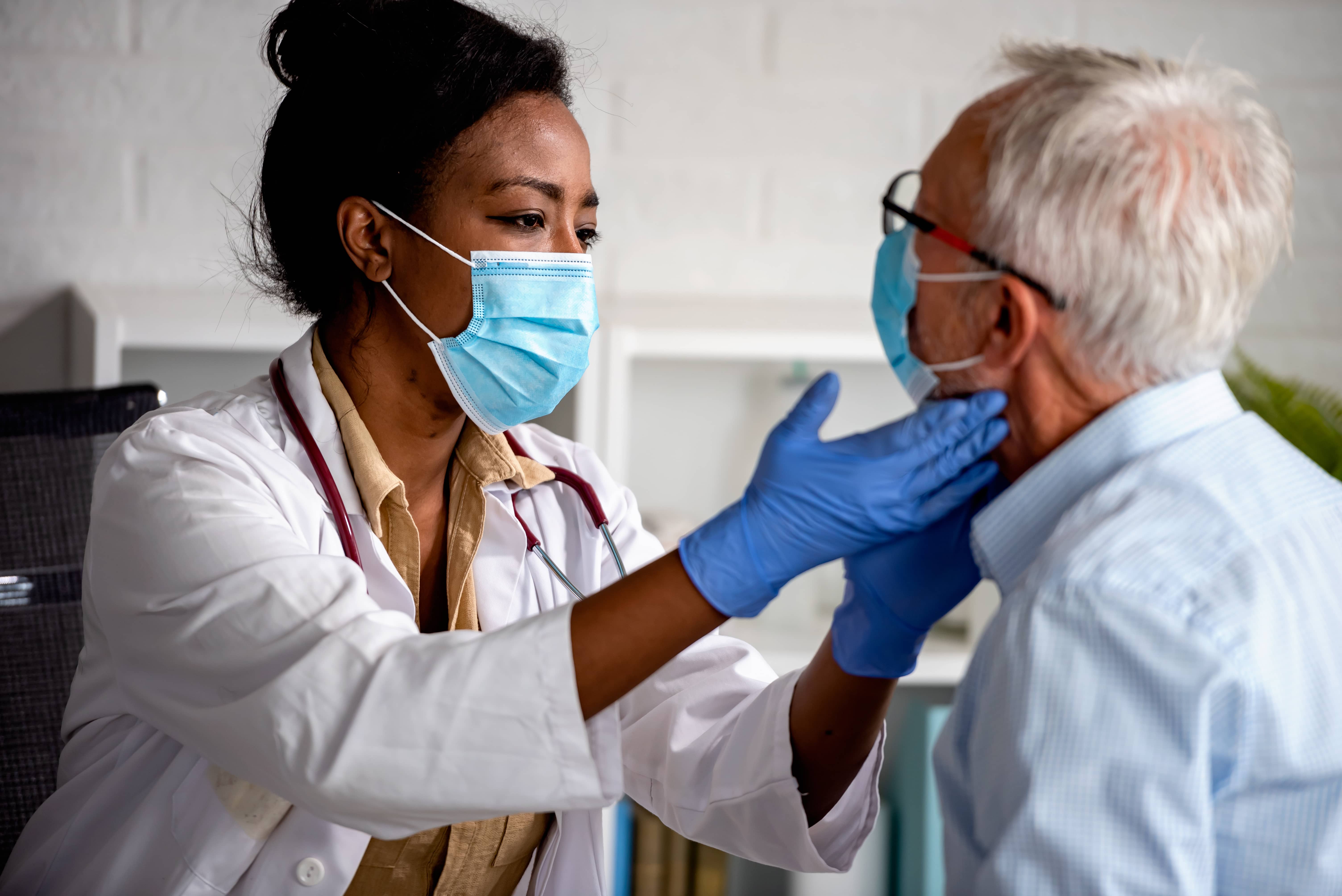 A female doctor in a mask examines an elderly man