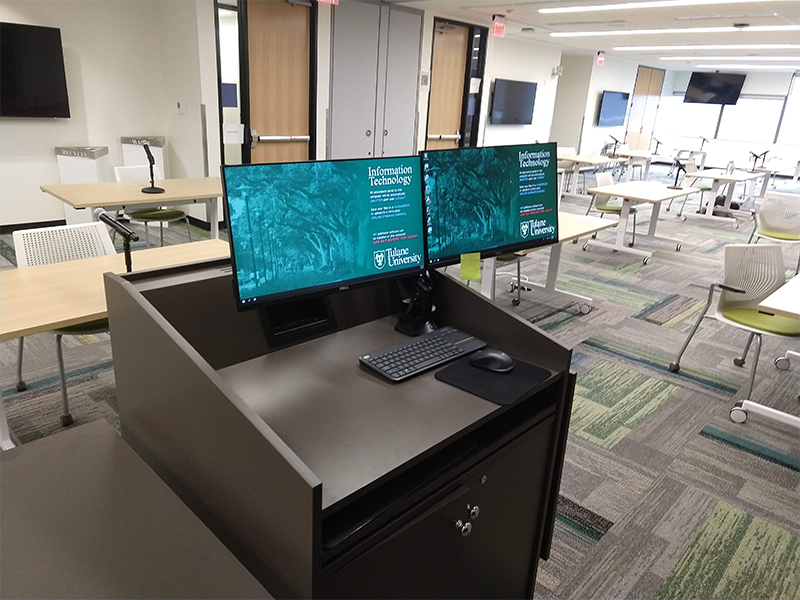 Two Monitors stand on a desk with informational technology screens visible