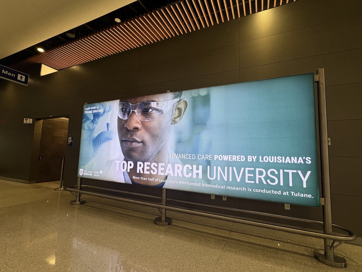 Backlit ad in a modern terminal featuring a researcher for Tulane University Scchol of Medicine