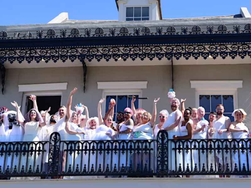 This image shows a group of people in wedding dresses standing on a balcony