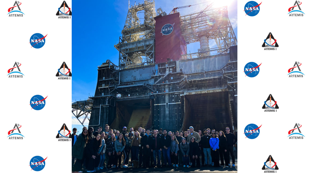 This image shows a group of people standing in front of a NASA facility.
