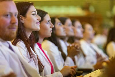 students on white coat day listening to the speaker
