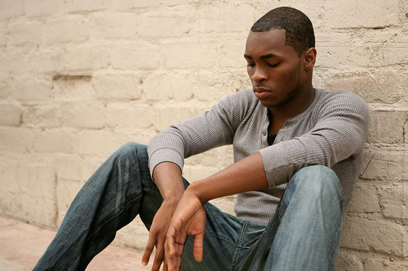 african-american male leaning on brick wall