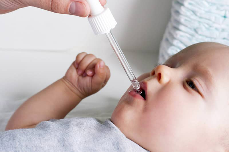 Baby getting medicine from a dropper
