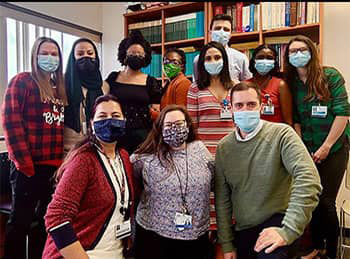 residents with masks in front of a bookcase