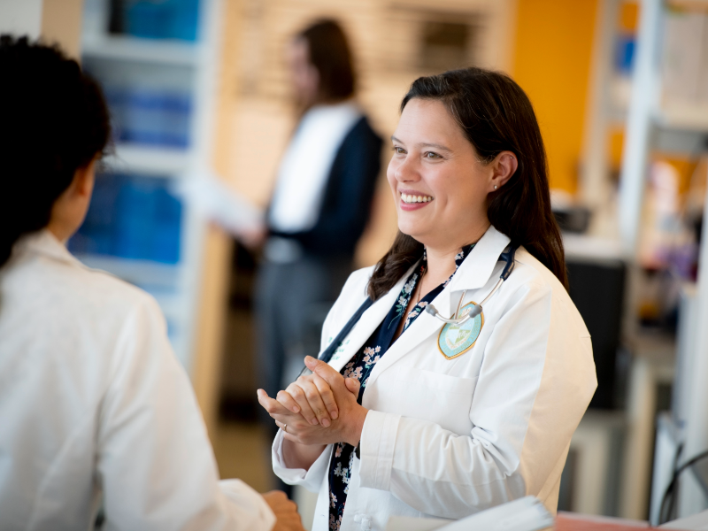 This is a photo of a physician in a white coat talking to another physician