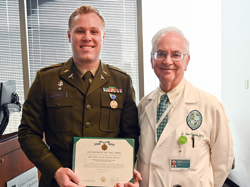 This is an image of a student in an Army uniform standing next to a man in a physician's white coat