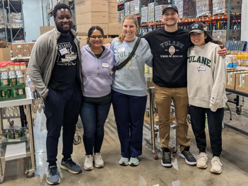 Five people posing for a picture inside a warehouse