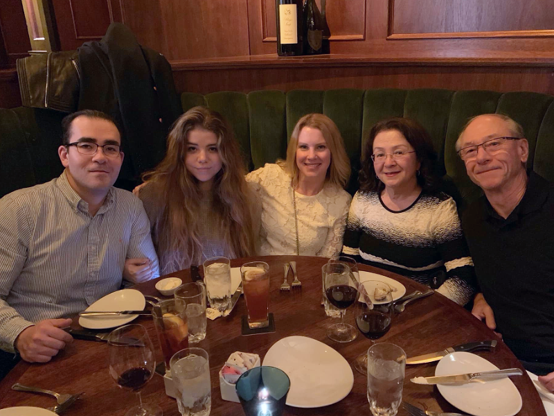 Five people sitting around a table with glasses and plates on it