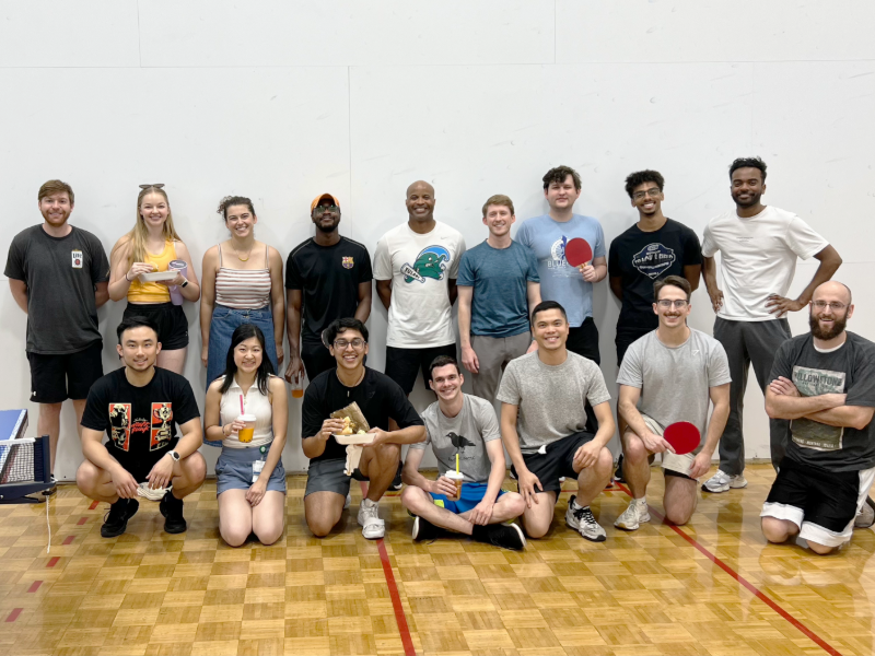 A group of people sitting and standing on an indoor court