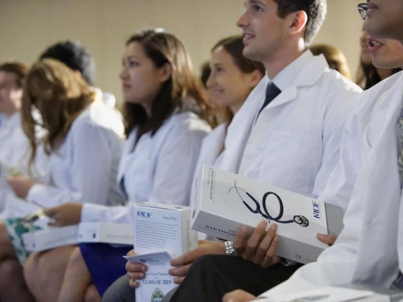A row of people wearing white doctors coats 