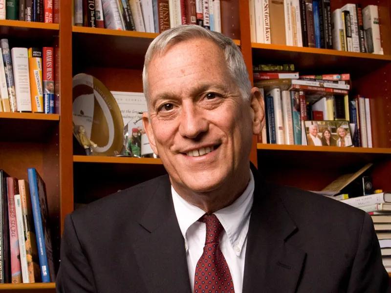 A headshot of Walter Isaacson in front of a bookcase