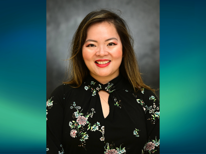 A portrait of Dr. Vy Anh Mai. She's wearing a black shirt with flowers on it