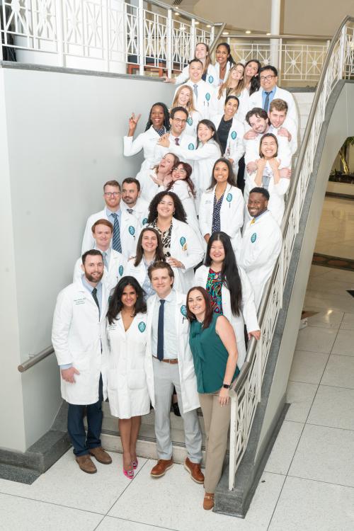 a group of surgery residents stand on a staircase and smile 