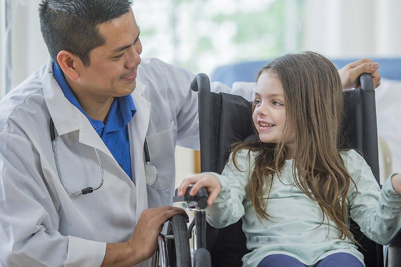 doctor talking to small girl in wheelchair