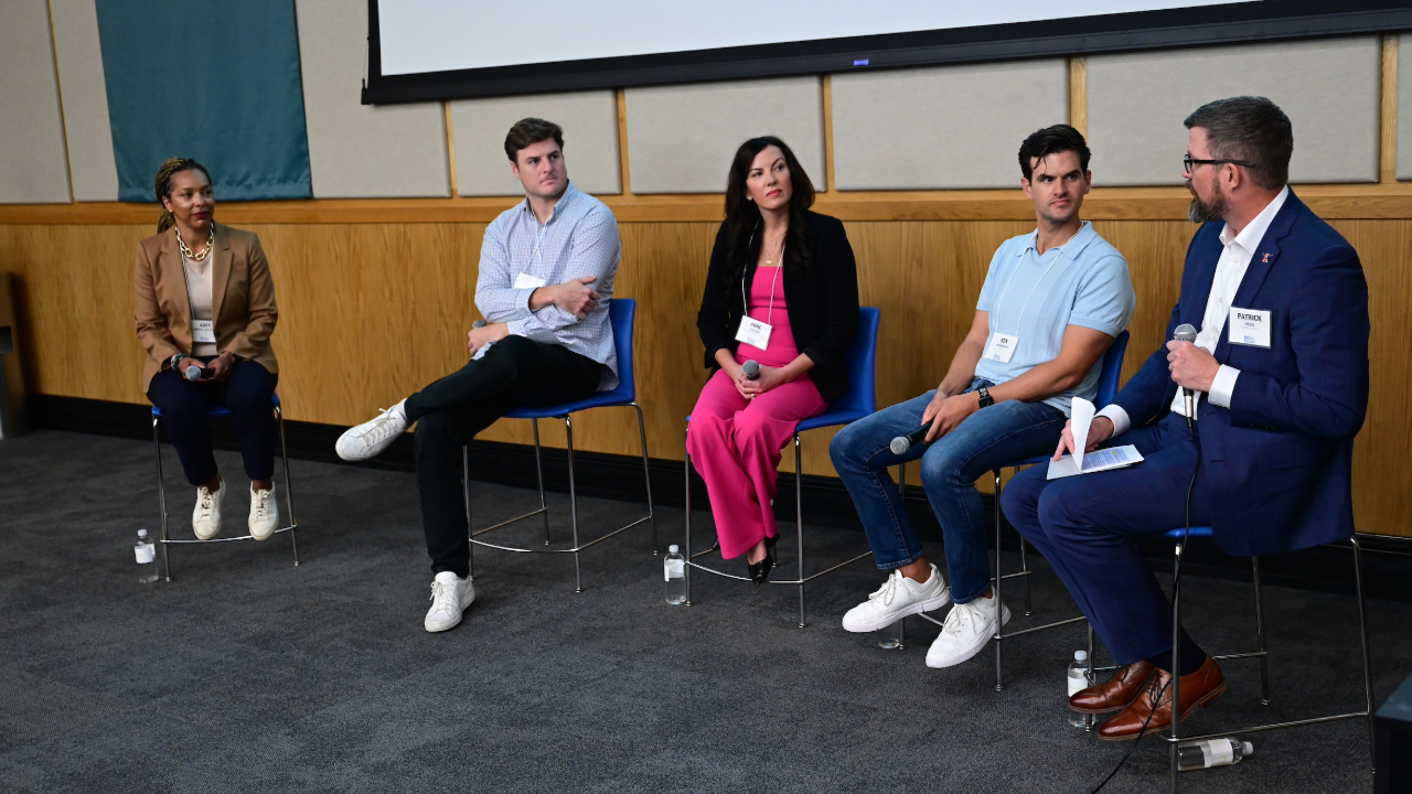 This image shows a panel of people presenting at a conference