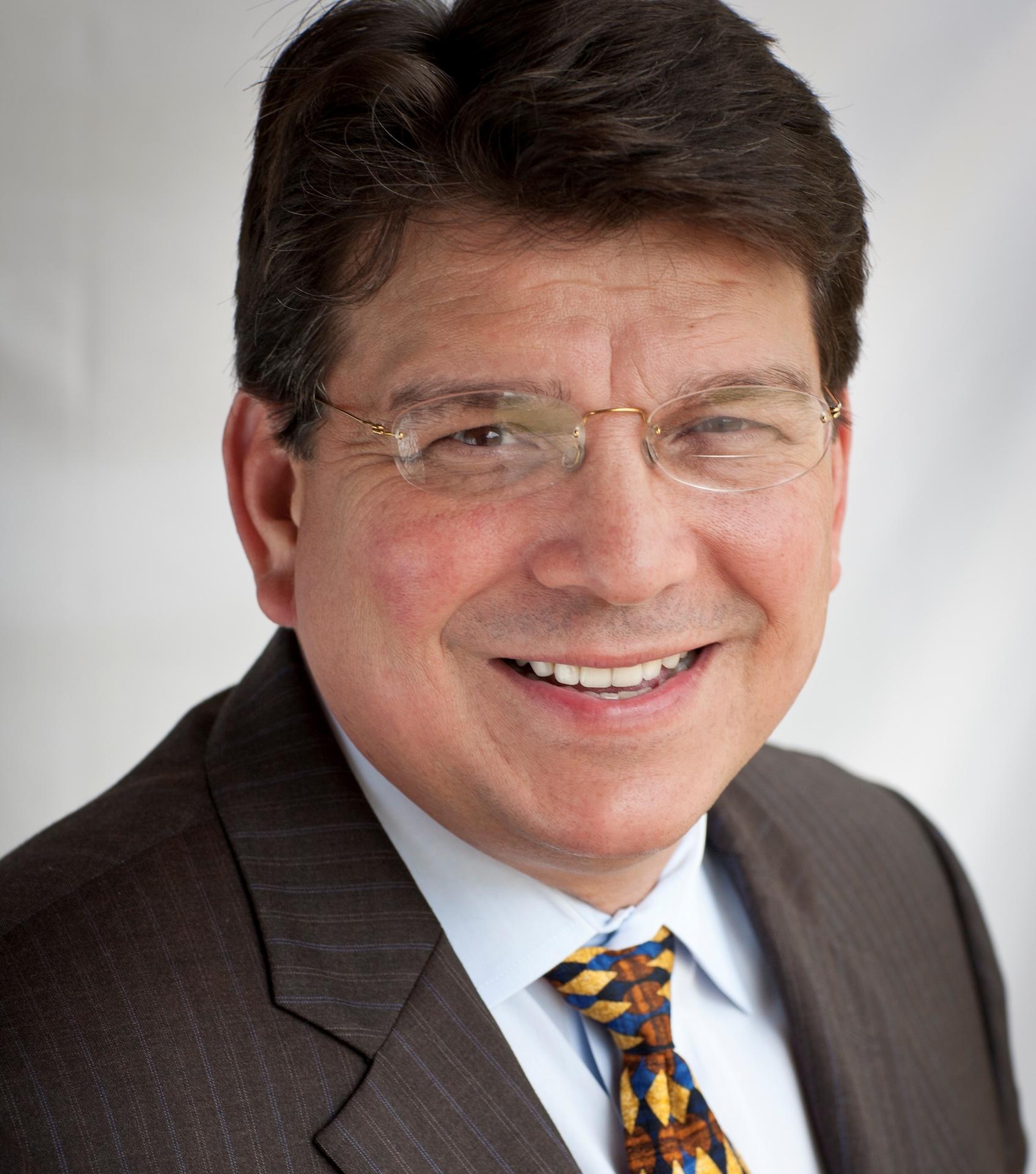 A man wearing glasses and a coat and tie