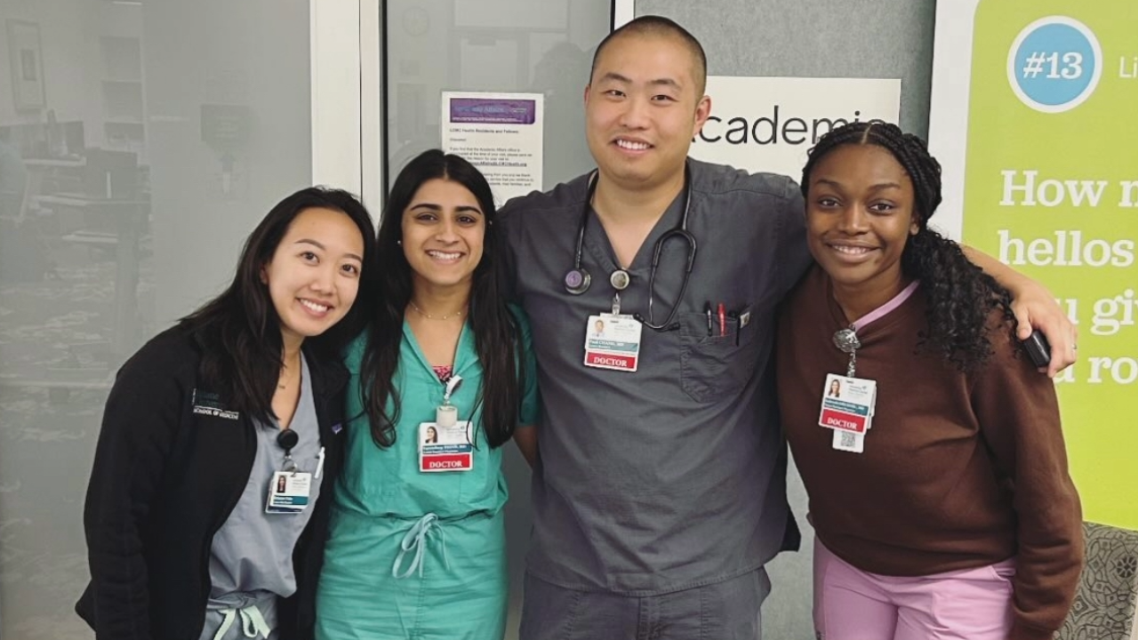 Four people in medical scrubs posing with their arms around each other