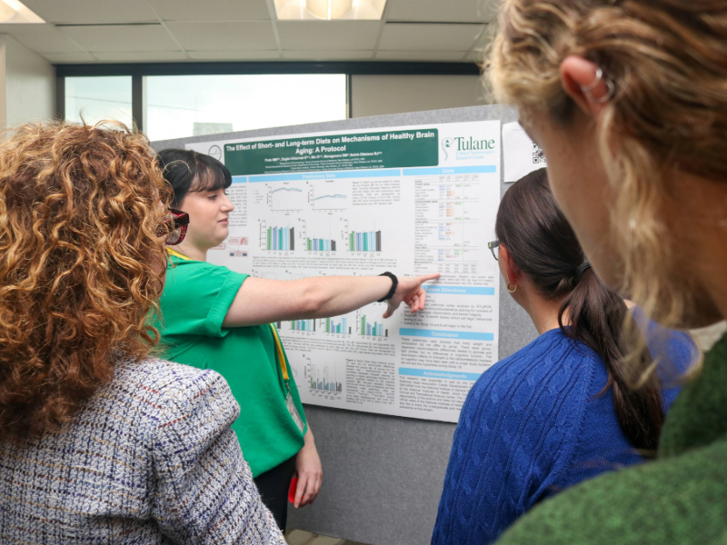 A woman points to a research poster and three other women watch