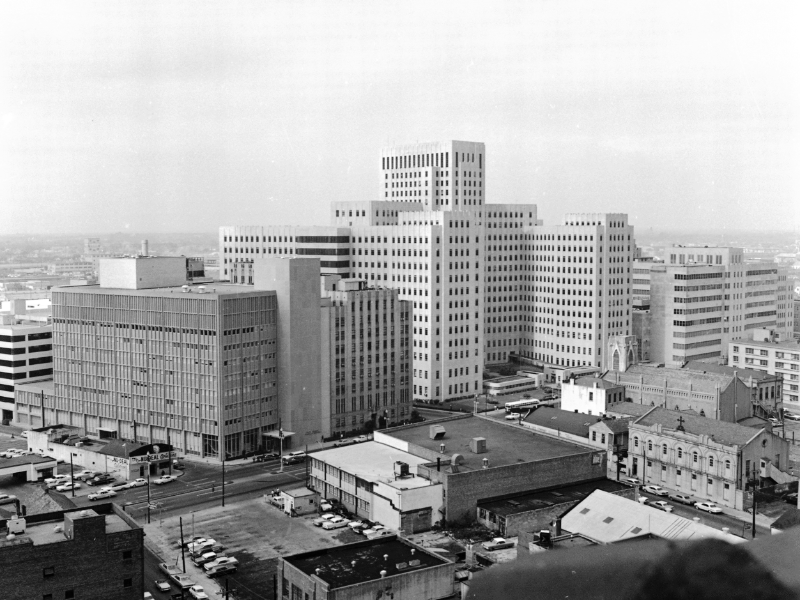 A black and white photos shows a downtown setting with the Hutchinson Building and Charity Hospital
