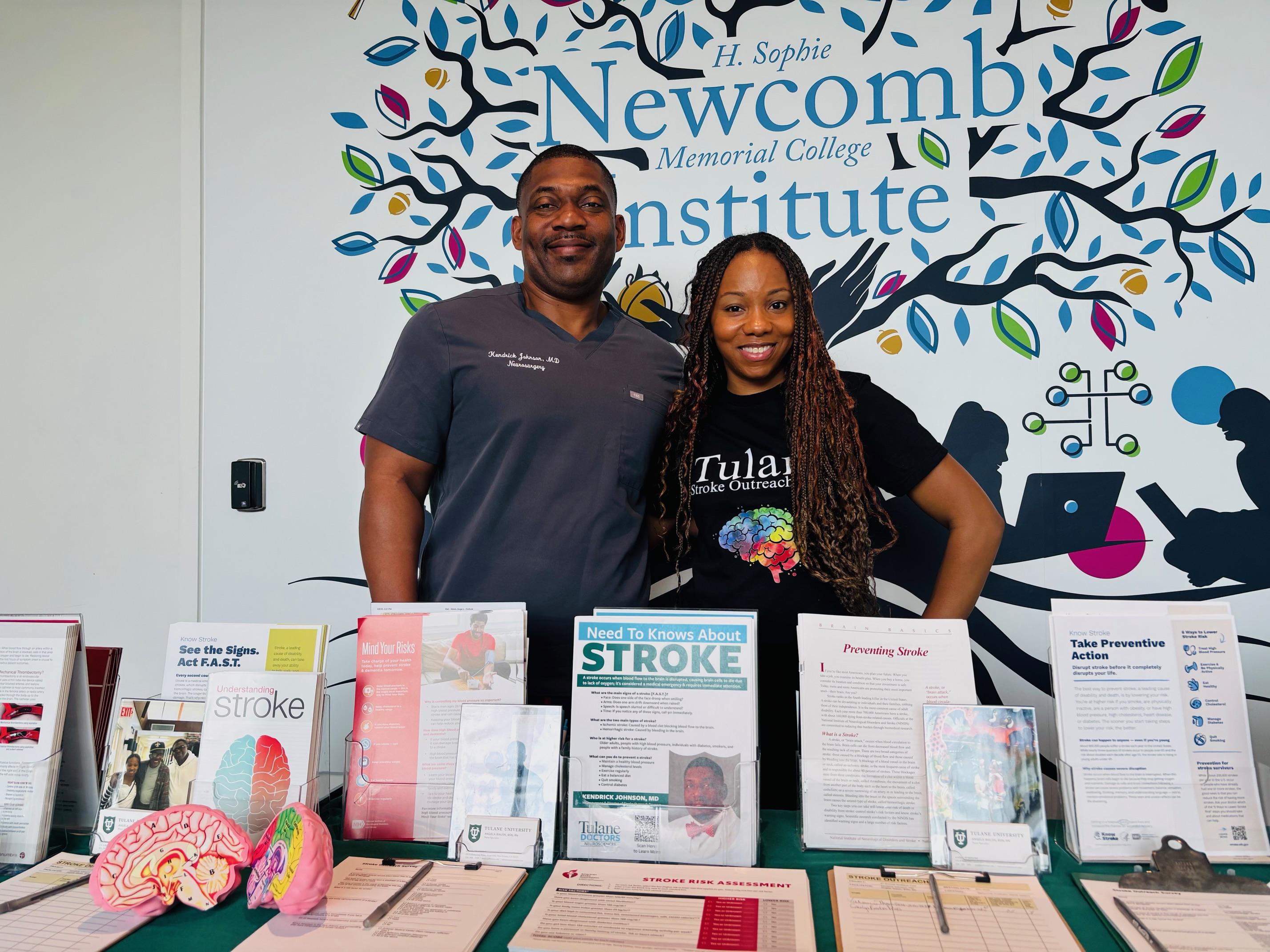 Two people stand behind a table displaying information about strokes