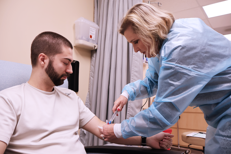 Nurse administering therapy in a man's arm.