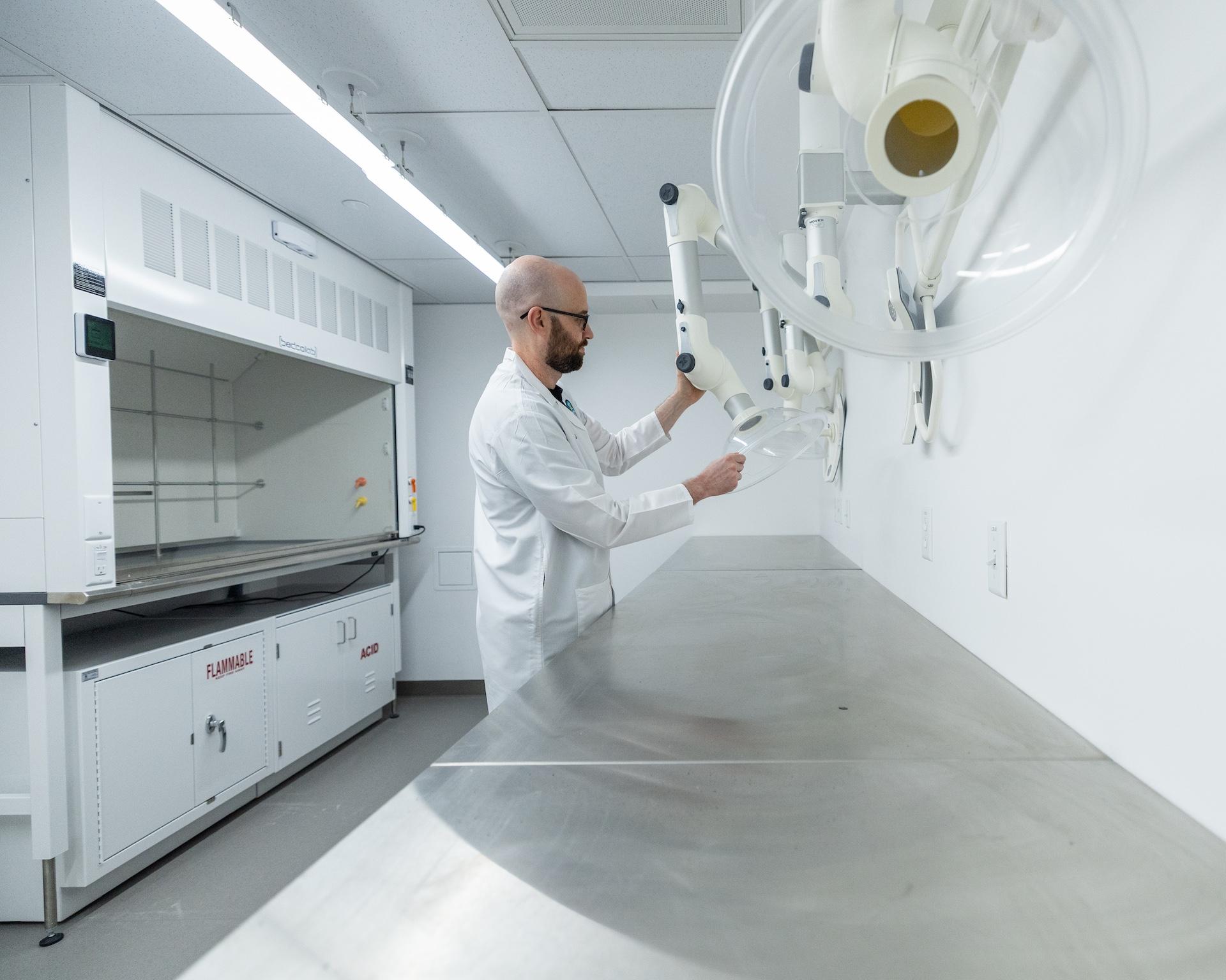 A researcher in a white lab coat adjusts laboratory equipment inside a newly renovated research lab.