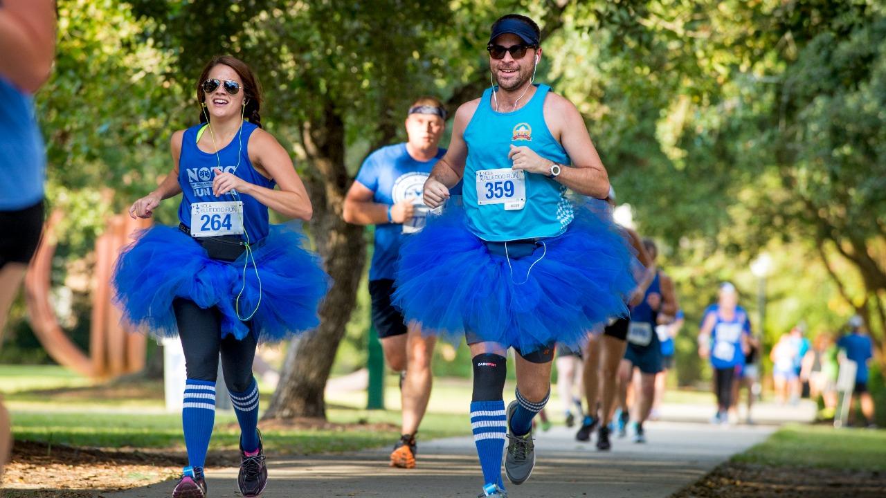 Pictured: male and female runners in blue tank tops, tutus and tube socks, participate in the event. 