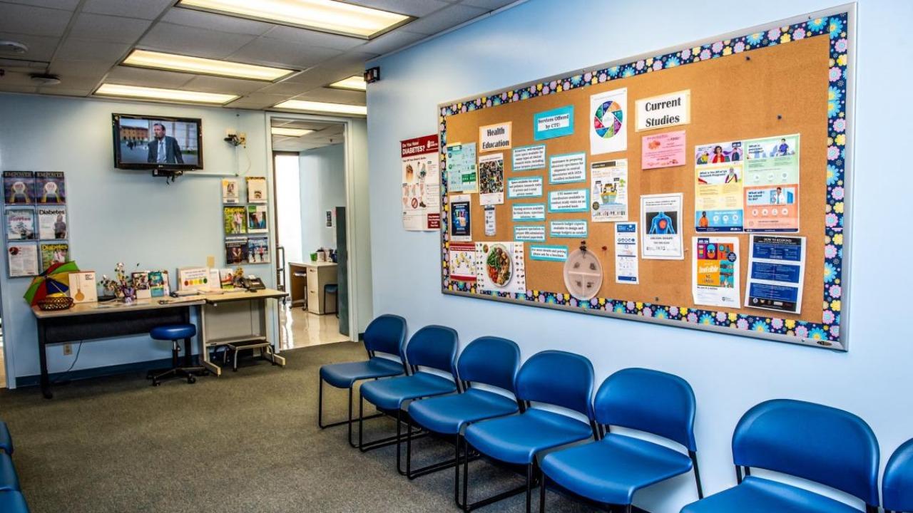 A waiting room with a bulletin board featuring information about clinical trials.