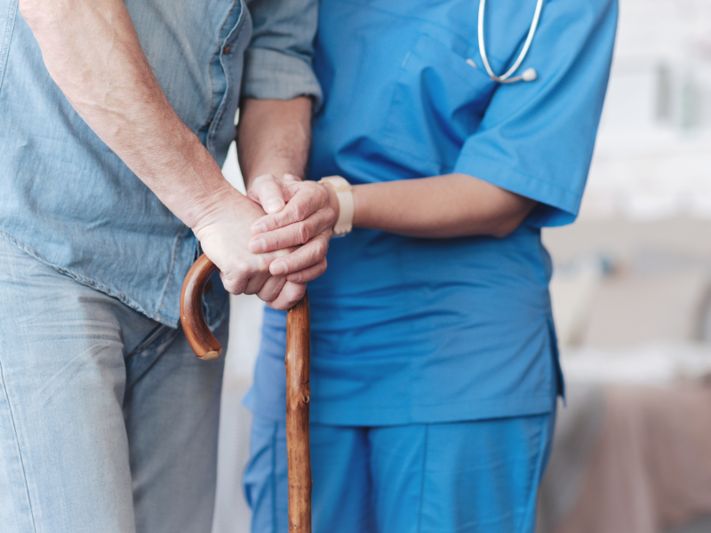 This image shows a healthcare worker helping an elderly person