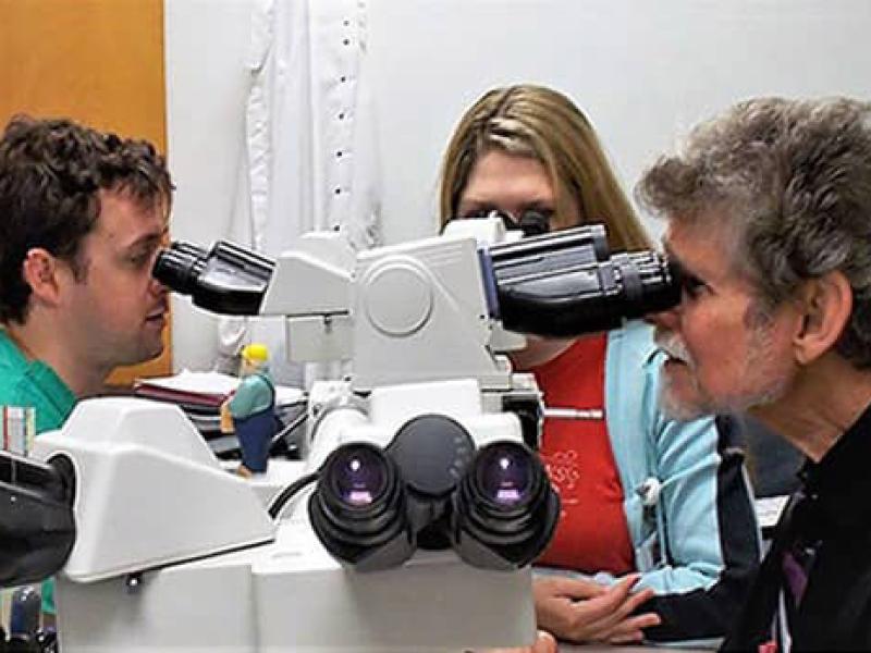 Dr. Daroca with 2 students looking in microscope