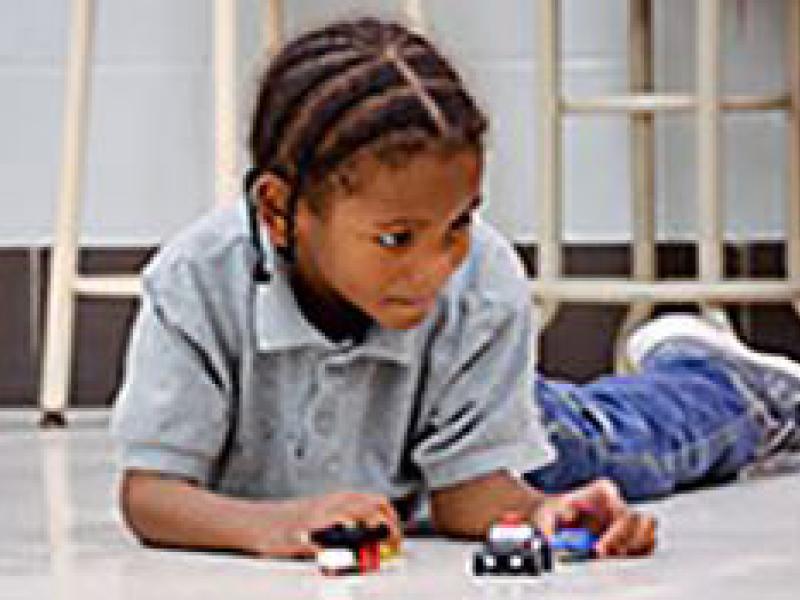 child on floor playing with trucks