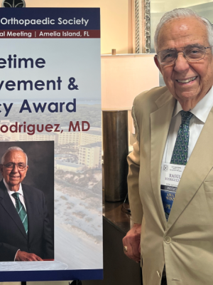 Dr. Rodriguez stands next to a poster announcing his award