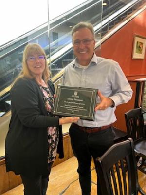 A woman Tammy Naramore receives an award from a man celebrating her 20 years at Tulane