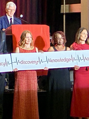 Four people stand holding signs reading "Advocacy, Discovery, Knowledge, and Access"